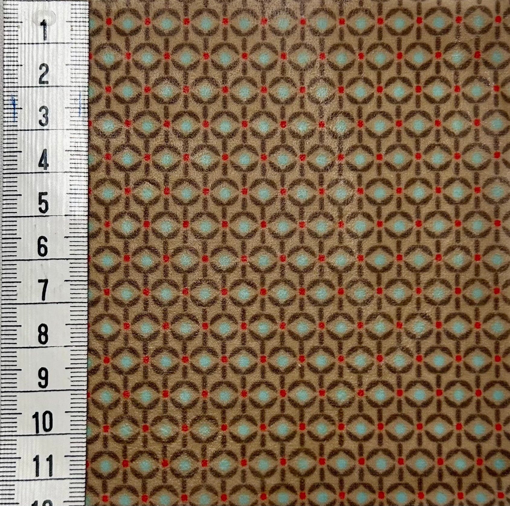 Bienenwachs-Stoffmuster hellbraun, hellblau, rotem Retro-Muster Zentimetermaß links am Rand
